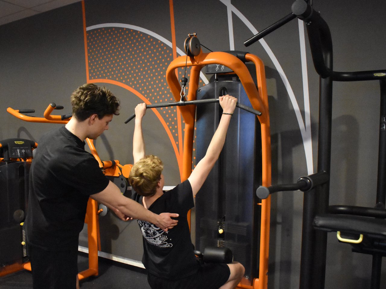 Personal trainer Jason begeleidt een klant bij de lat pulldown in de sportschool in Almere