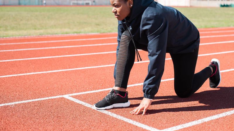 Een vrouw staat klaar voor de start van een sprint op een atletiekbaan